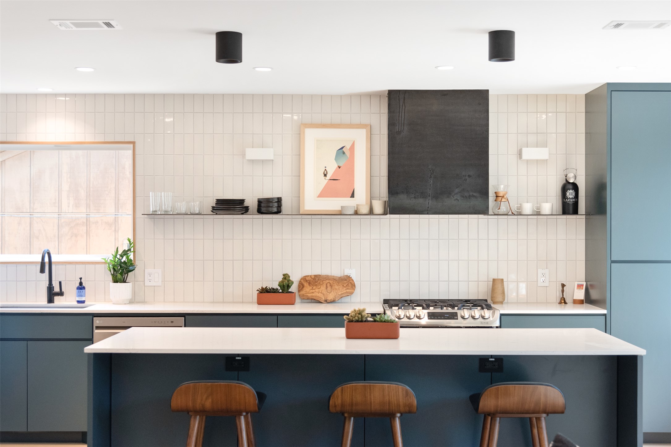 2815 Goldbridge Drive Austin, TX 78745 - Photo 26 of 40 Kitchen featuring a kitchen breakfast bar, blue cabinetry, a kitchen island, backsplash, and light stone countertops
