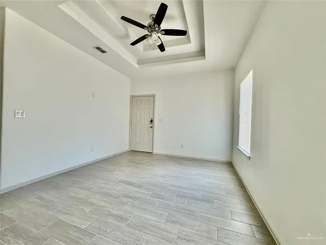 an empty room with a ceiling fan and window