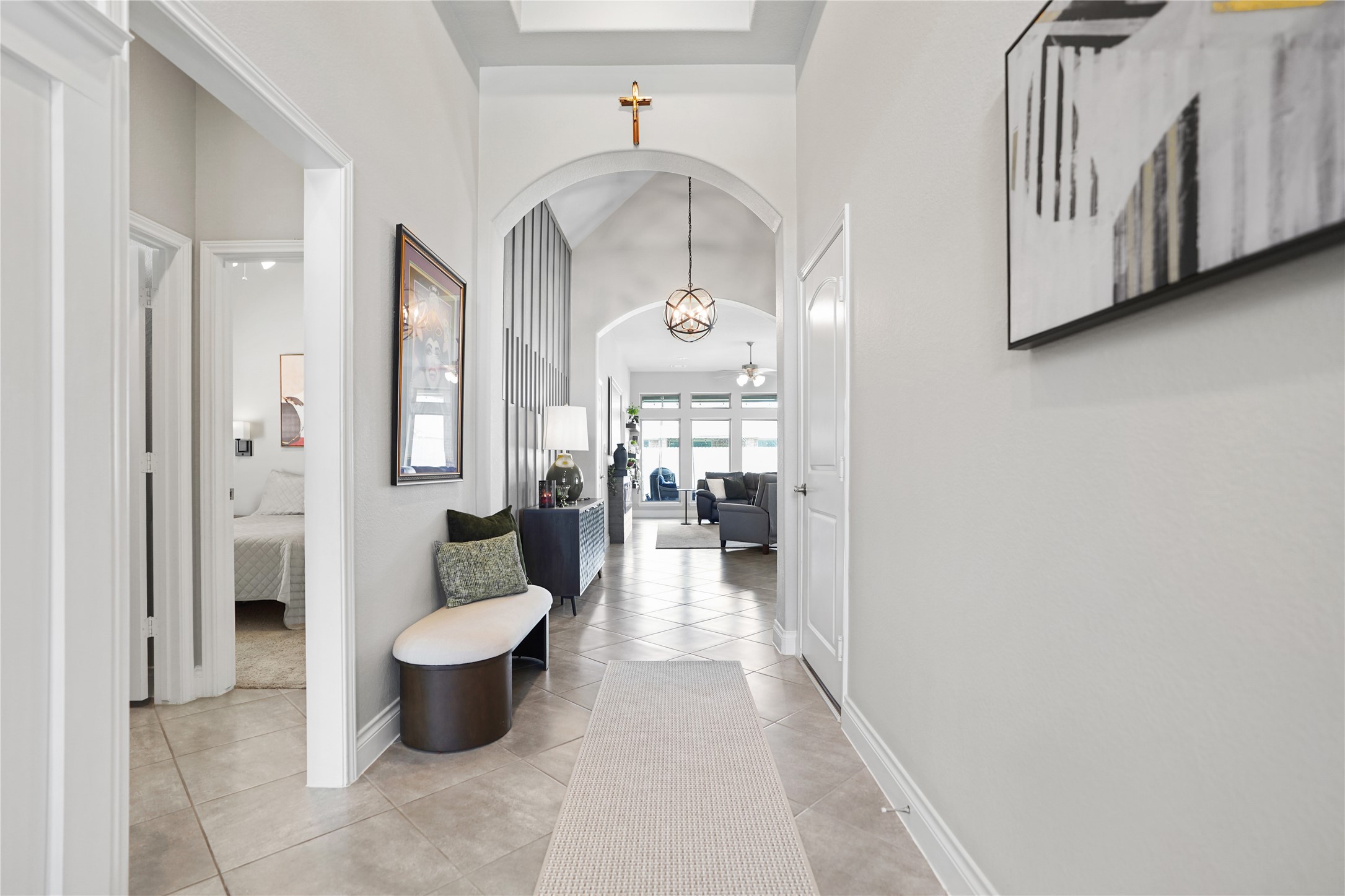 2345 Redwood Ridge Trail Manvel, TX 77578 - Photo 6 of 39 This inviting hallway features a tiled floor, high ceilings, and modern lighting. It leads to a bright living area with large windows, offering a glimpse of a cozy, open-concept interior.