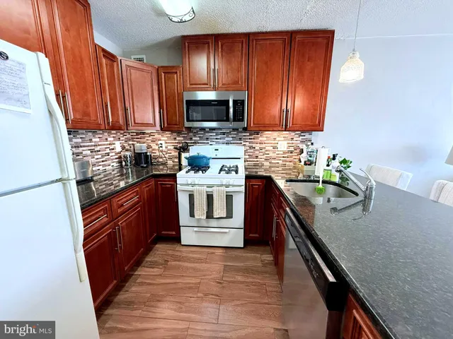 a kitchen with stainless steel appliances granite countertop wooden cabinets a stove top oven a sink and dishwasher