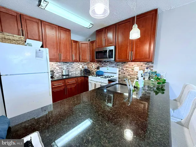 a kitchen with granite countertop a sink a stove and a refrigerator