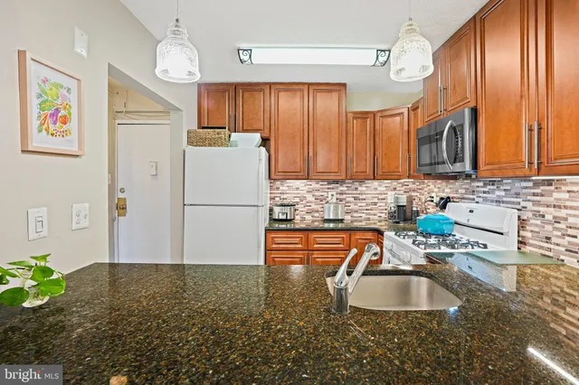 a kitchen with kitchen island granite countertop a sink a center island cabinets and stainless steel appliances