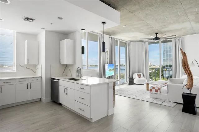 a large white kitchen with a large window and stainless steel appliances