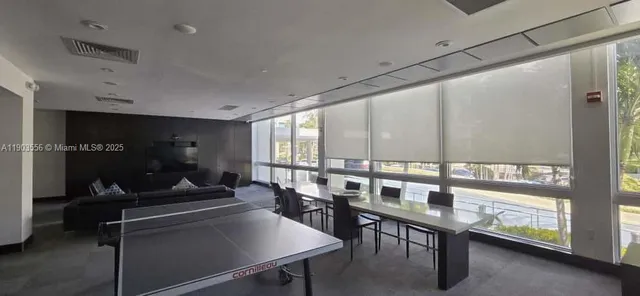 a room with lots of tables a large window and chairs