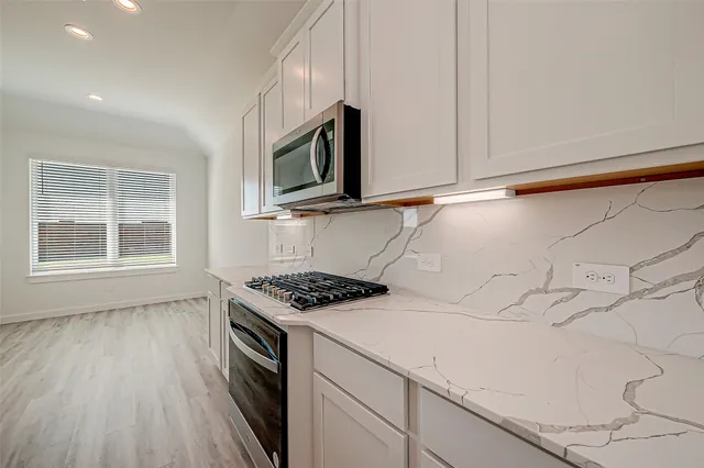 a kitchen with stainless steel appliances a stove a microwave and a hard wood floor