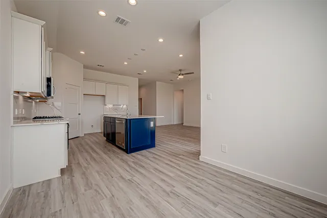 a large kitchen with a wooden floor and stainless steel appliances