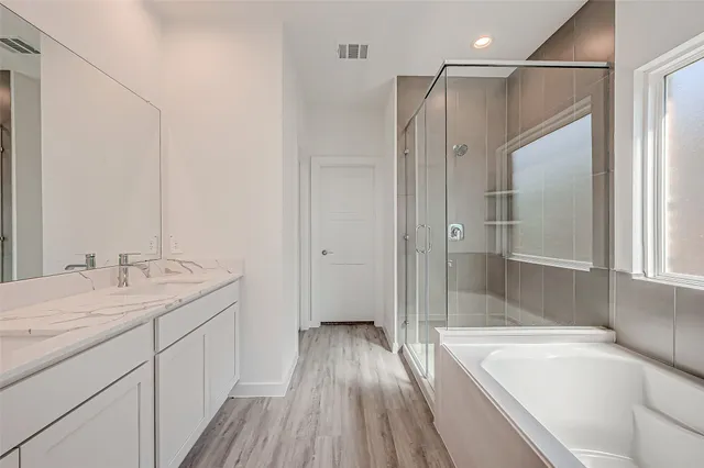 a spacious bathroom with a granite countertop sink mirror bathtub and shower