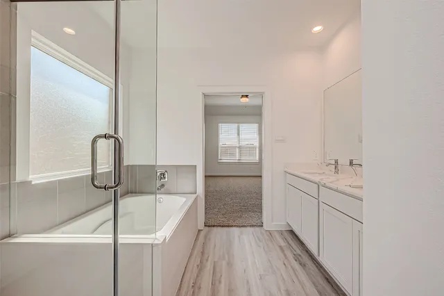 a bathroom with a sink and mirror with bathtub