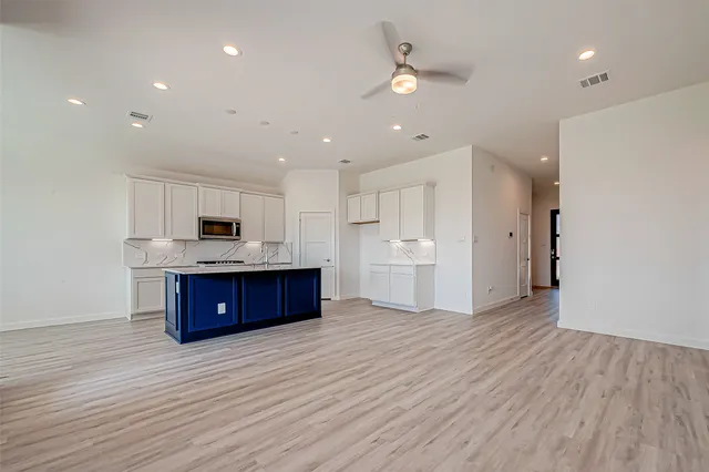 a large kitchen with stainless steel appliances kitchen island a large counter top and a wooden floors