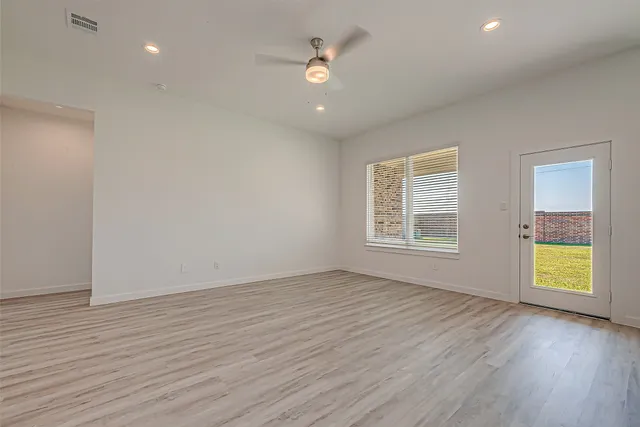an empty room with wooden floor and windows