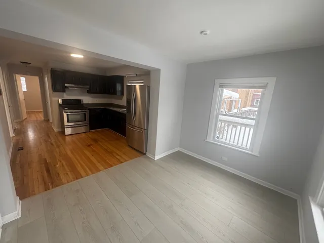 a view of a kitchen center island with stainless steel appliances wooden floor and living room view