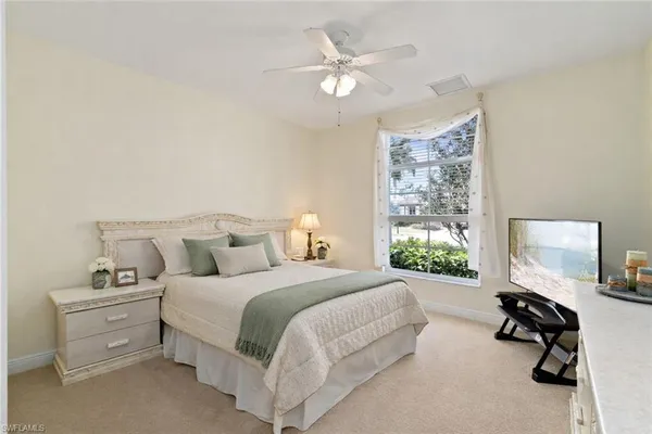 a bedroom with a bed a large window and furniture