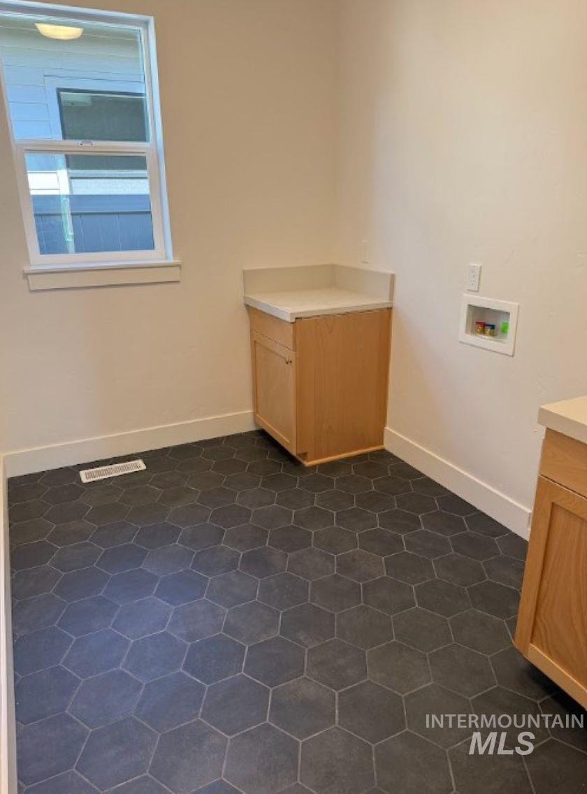 755 West Wrangler Street Meridian, ID 83646 - Photo 15 of 35 Spacious utility room featuring hexagon tile flooring, light wood cabinetry with a light-toned countertop, and a window for natural light
