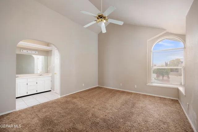 an empty room with a window and a chandelier fan