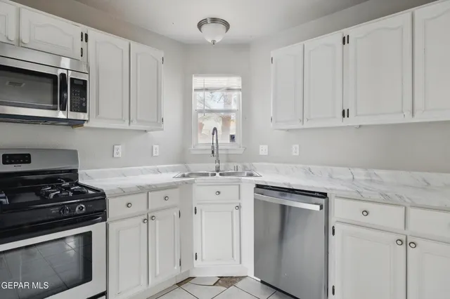 a kitchen with granite countertop white cabinets and stainless steel appliances