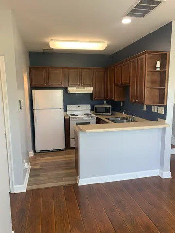 a kitchen with a refrigerator a stove and wooden floor