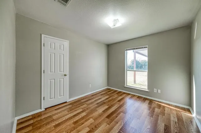 an empty room with wooden floor cabinet and windows