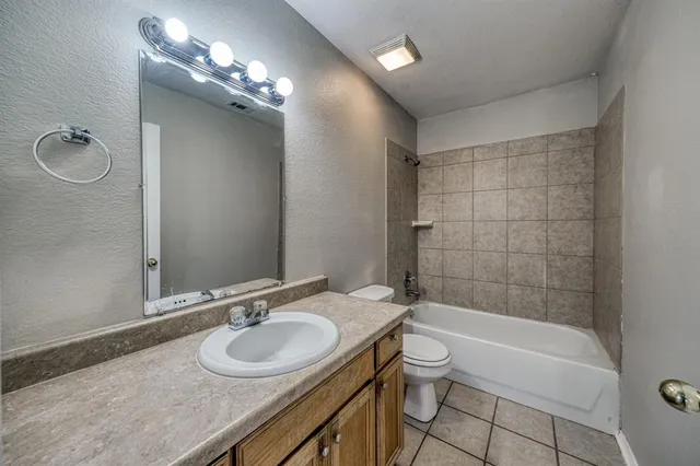 a bathroom with a granite countertop sink a toilet and shower