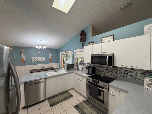 a kitchen with granite countertop a sink stove and microwave