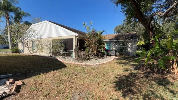 a view of a house with a yard and covered with tall trees