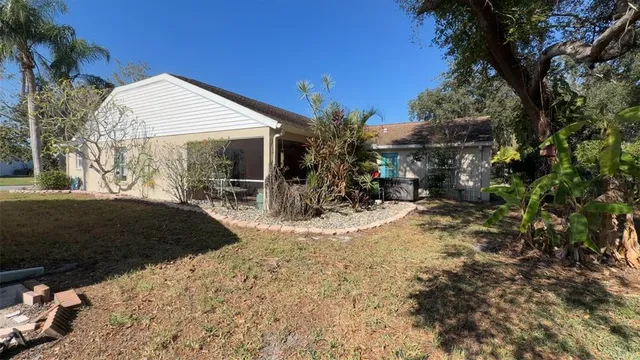 a view of a house with a yard and covered with tall trees
