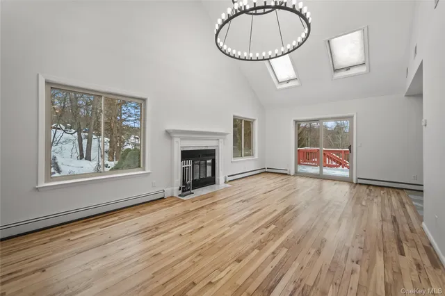 a view of an empty room with wooden floor fireplace and a window
