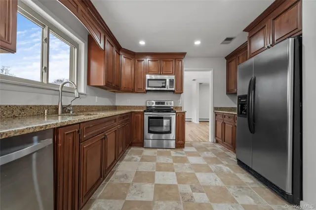 a kitchen with stainless steel appliances granite countertop a stove a sink and a refrigerator