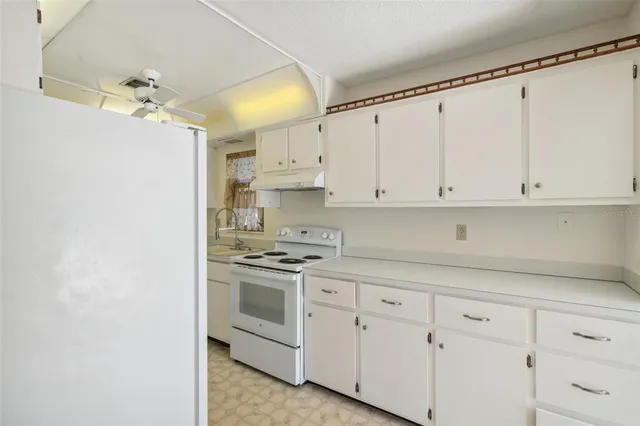 a kitchen with white cabinets and white appliances