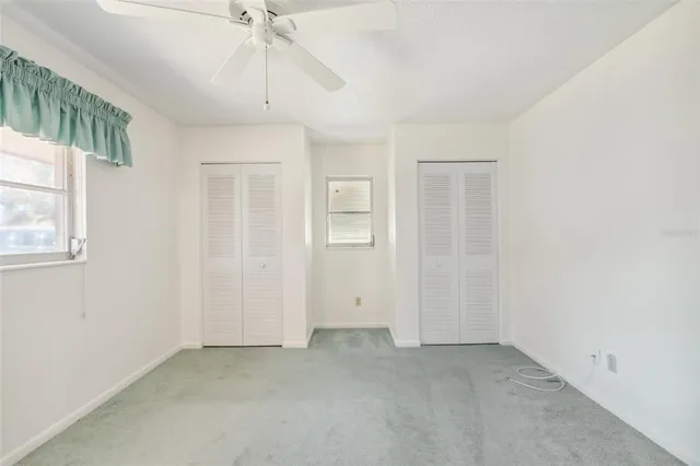 an empty room with a chandelier fan and windows