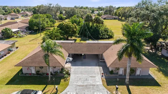 an aerial view of a house with swimming pool and large trees