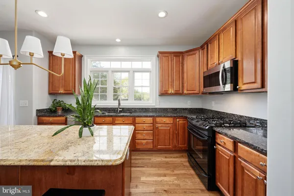 a kitchen with stainless steel appliances a refrigerator a stove a sink dishwasher and a dining table with wooden floor