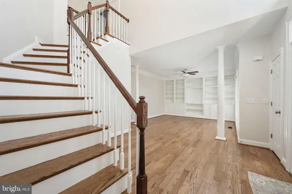 an empty room with wooden floor chandelier fan and windows