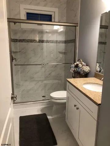 a bathroom with a granite countertop sink a toilet and shower