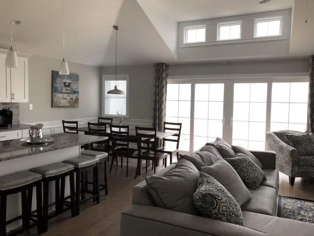a living room with furniture kitchen view and a window