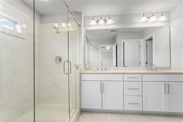 a bathroom with a double vanity sink mirror and shower