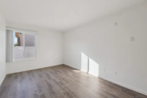 a view of an empty room with wooden floor and windows