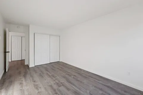 a view of an empty room with wooden floor and closet