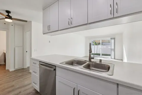 a kitchen with stainless steel appliances granite countertop a sink and a white cabinets with wooden floor