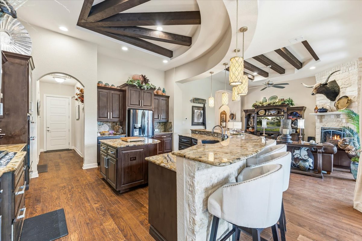 1930 Rothschild New Braunfels, TX 78132 - Photo 12 of 39 The kitchen features an island with a breakfast bar, granite countertops, and dark wood cabinetry