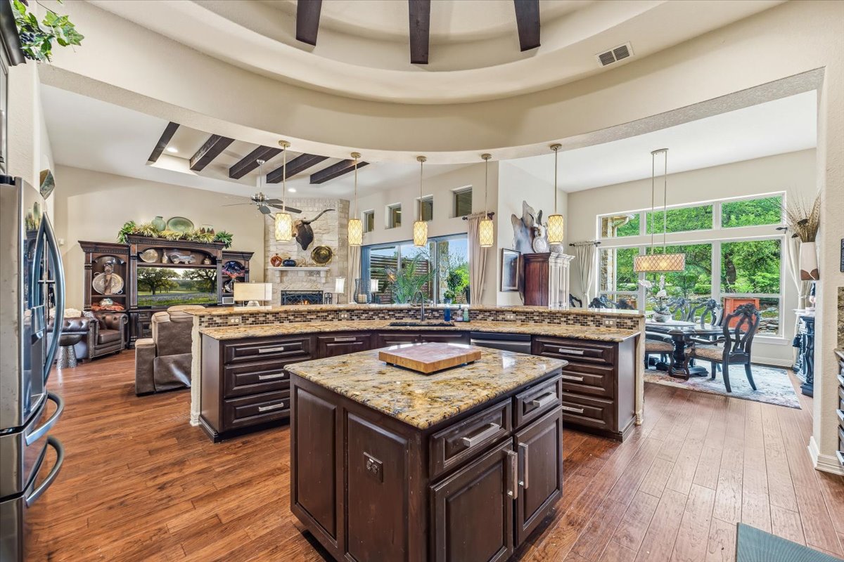 1930 Rothschild New Braunfels, TX 78132 - Photo 13 of 39 The property features an open-concept living space with hardwood floors, a kitchen island with a granite countertop, and dark wood cabinetry