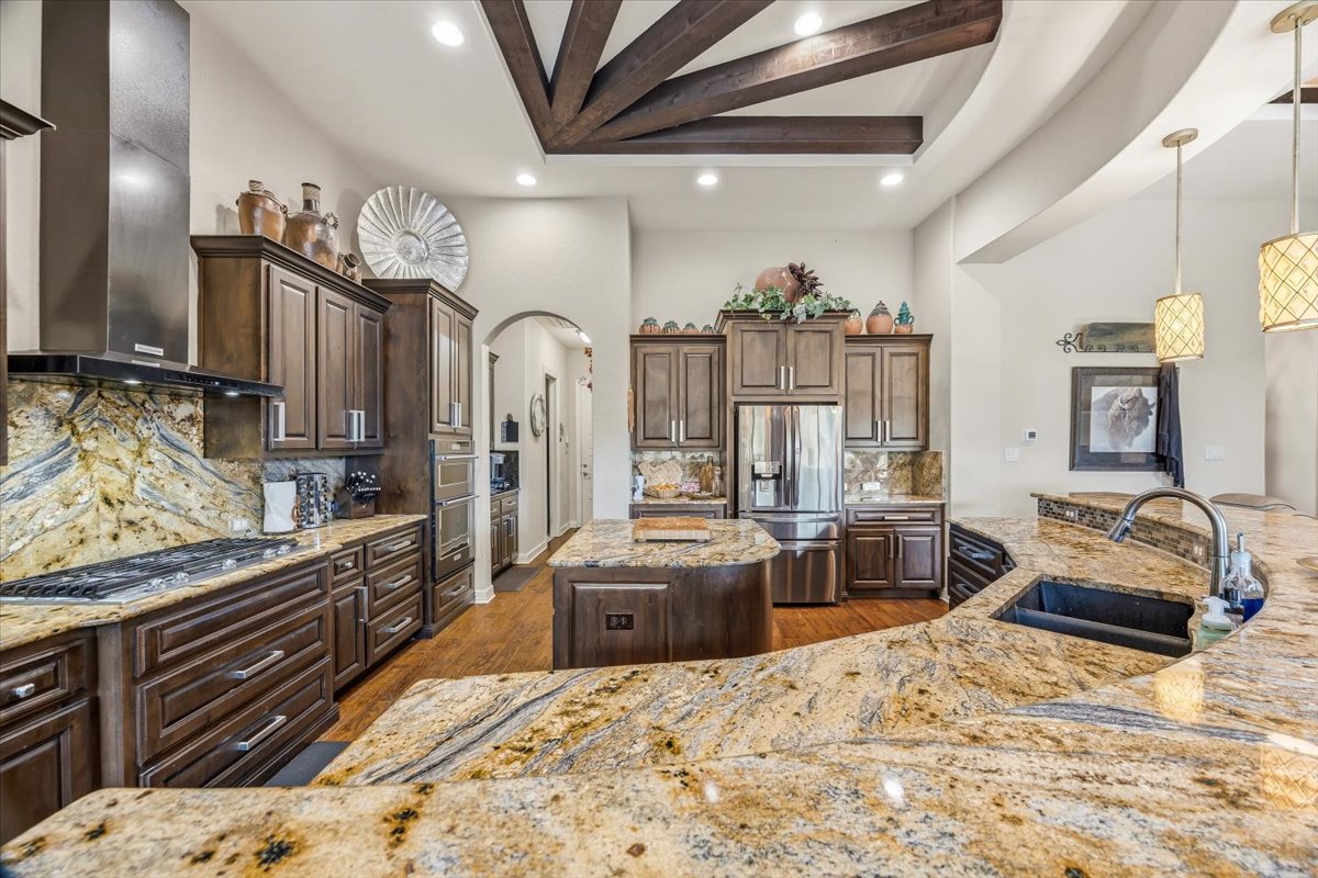 1930 Rothschild New Braunfels, TX 78132 - Photo 14 of 39 The kitchen features extensive granite countertops, dark wood cabinetry, a stainless steel range hood, and recessed lighting