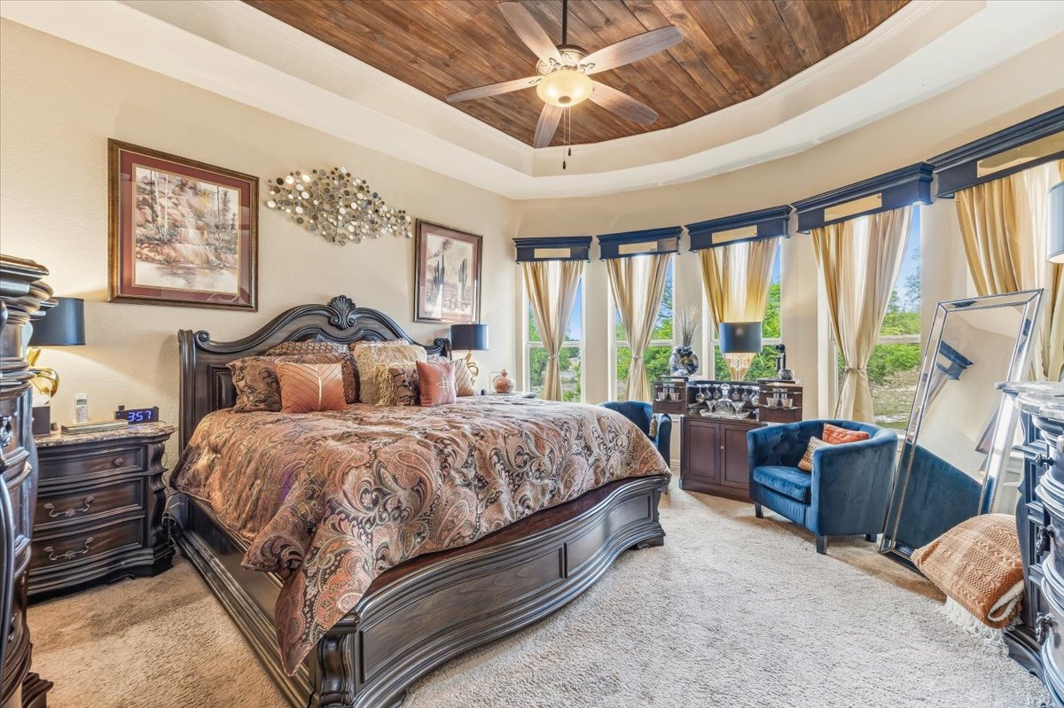 1930 Rothschild New Braunfels, TX 78132 - Photo 23 of 39 Spacious room with a tray ceiling featuring wood paneling and a ceiling fan, bay windows with drapes, and carpeted floors