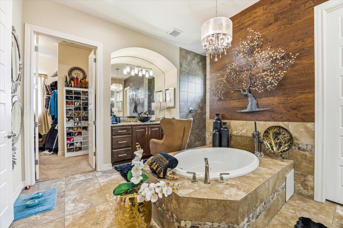 1930 Rothschild New Braunfels, TX 78132 - Photo 26 of 39 This bathroom features a spacious built-in tub with a tiled surround, a chandelier providing illumination, and a vanity with a large mirror