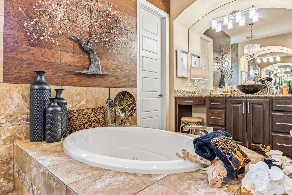 1930 Rothschild New Braunfels, TX 78132 - Photo 27 of 39 The bathroom features a built-in oval soaking tub with tiled surround, a vanity with a vessel sink and granite countertop, and a decorative wall accent