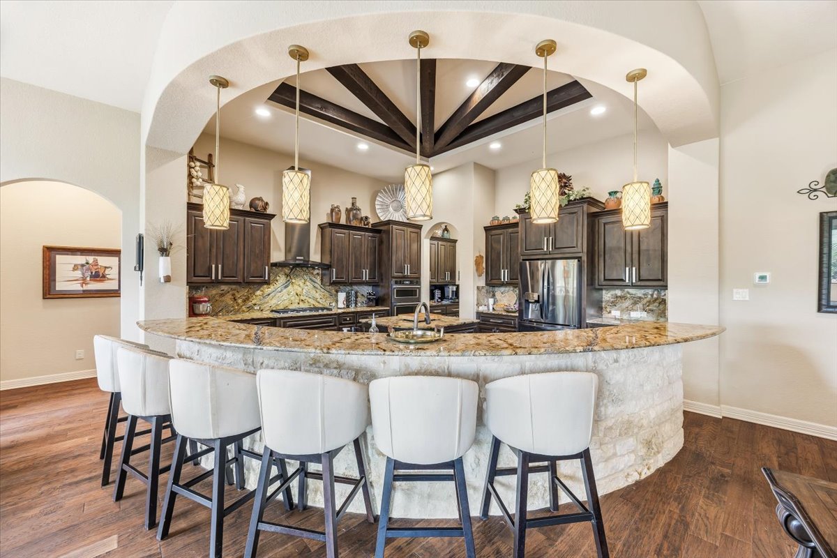 1930 Rothschild New Braunfels, TX 78132 - Photo 29 of 39 The kitchen features dark wood cabinetry, stainless steel appliances, and a granite countertop with a stone-faced bar area