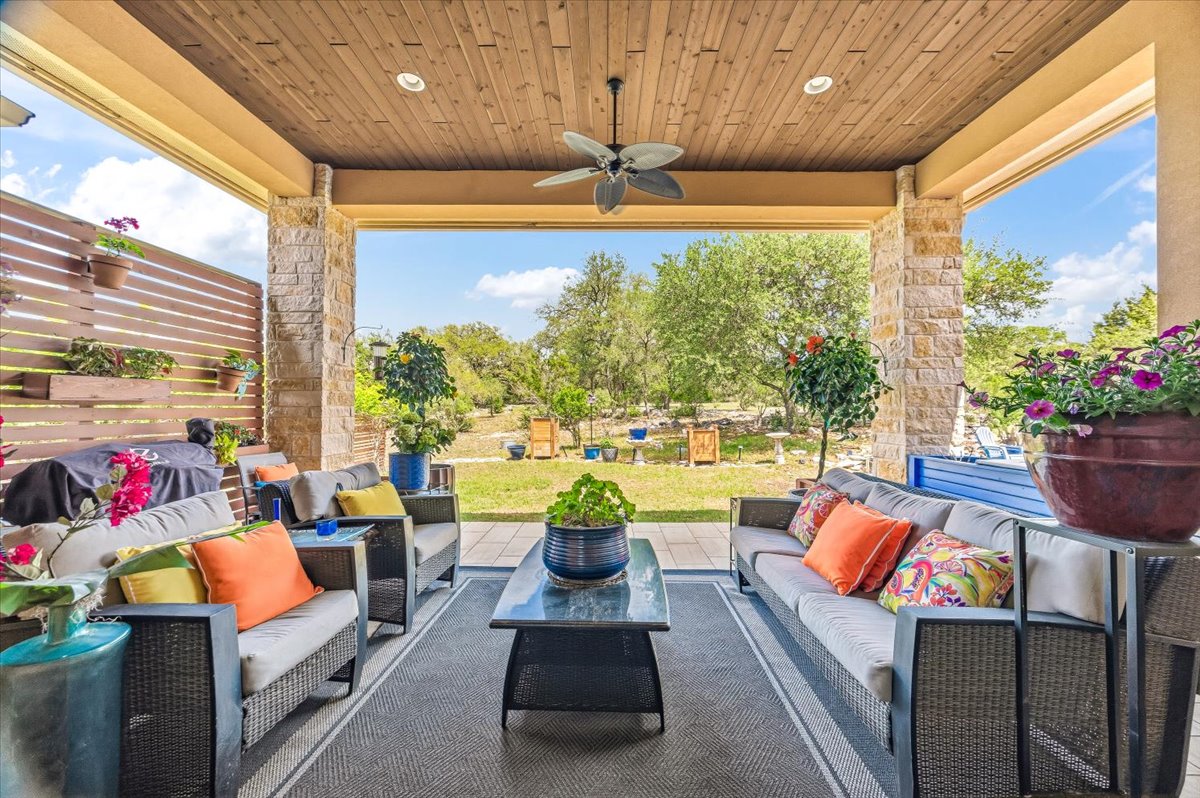 1930 Rothschild New Braunfels, TX 78132 - Photo 30 of 39 Expansive covered patio featuring a wood plank ceiling, a ceiling fan, and stone accent pillars, overlooking a large grassy area with mature trees