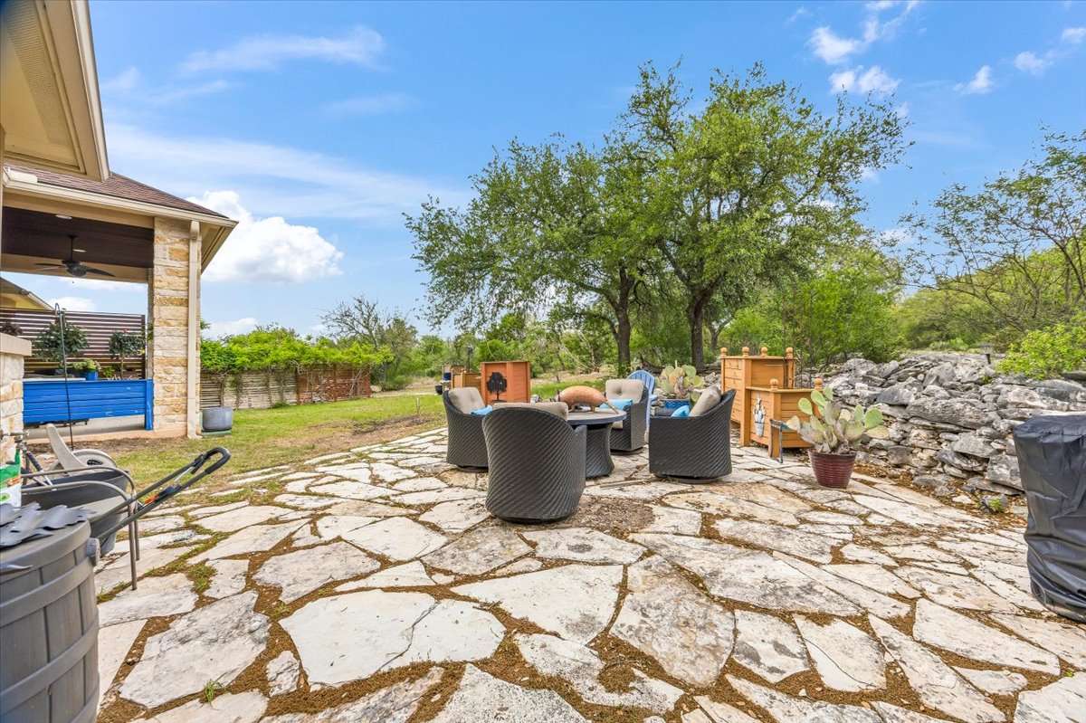 1930 Rothschild New Braunfels, TX 78132 - Photo 32 of 39 Expansive stone patio with outdoor seating, surrounded by lush trees and natural rock formations