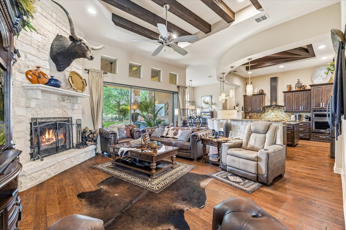 1930 Rothschild New Braunfels, TX 78132 - Photo 9 of 39 The open concept living area features hardwood floors, a stone fireplace, and exposed wood beams on the ceiling