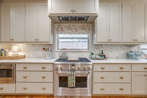 a kitchen with granite countertop white cabinets and white stainless steel appliances
