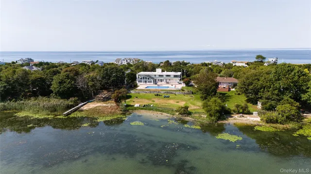 an aerial view of a houses with a yard and lake view